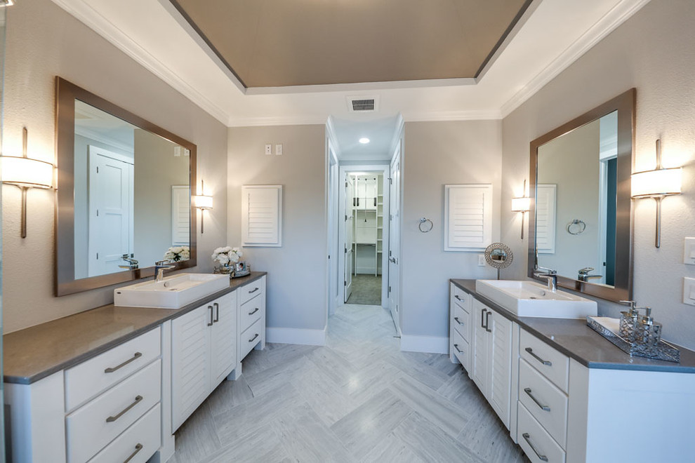 This is an example of a large traditional shower room bathroom in Houston with freestanding cabinets, white cabinets, a freestanding bath, a corner shower, a one-piece toilet, multi-coloured tiles, mosaic tiles, grey walls, porcelain flooring, a vessel sink and engineered stone worktops.