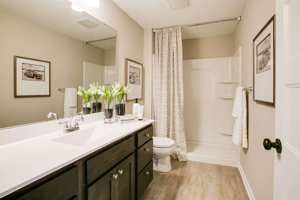 Bathroom - mid-sized transitional 3/4 medium tone wood floor and beige floor bathroom idea in Minneapolis with shaker cabinets, dark wood cabinets, a two-piece toilet, beige walls, an integrated sink and quartz countertops