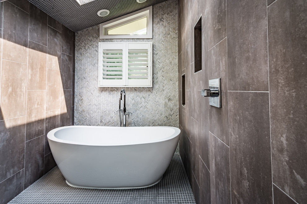 This is an example of a large contemporary ensuite wet room bathroom in St Louis with flat-panel cabinets, grey cabinets, a freestanding bath, a two-piece toilet, grey tiles, porcelain tiles, grey walls, porcelain flooring, a submerged sink and granite worktops.