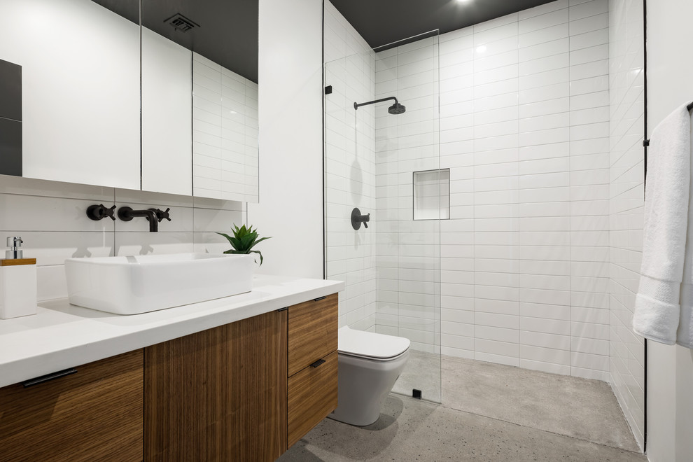 Exempel på ett mellanstort modernt vit vitt en-suite badrum, med släta luckor, skåp i mellenmörkt trä, ett fristående badkar, en hörndusch, vit kakel, keramikplattor, vita väggar, betonggolv, ett undermonterad handfat, bänkskiva i akrylsten, grått golv och dusch med gångjärnsdörr