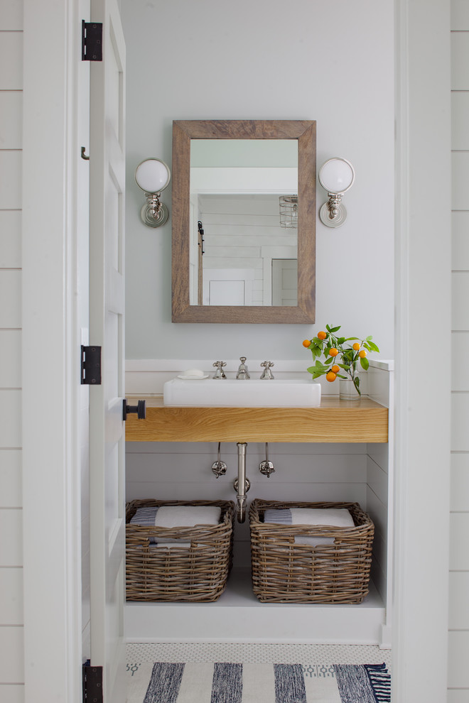 Example of a small beach style white floor and mosaic tile floor bathroom design with wood countertops, a vessel sink and white walls