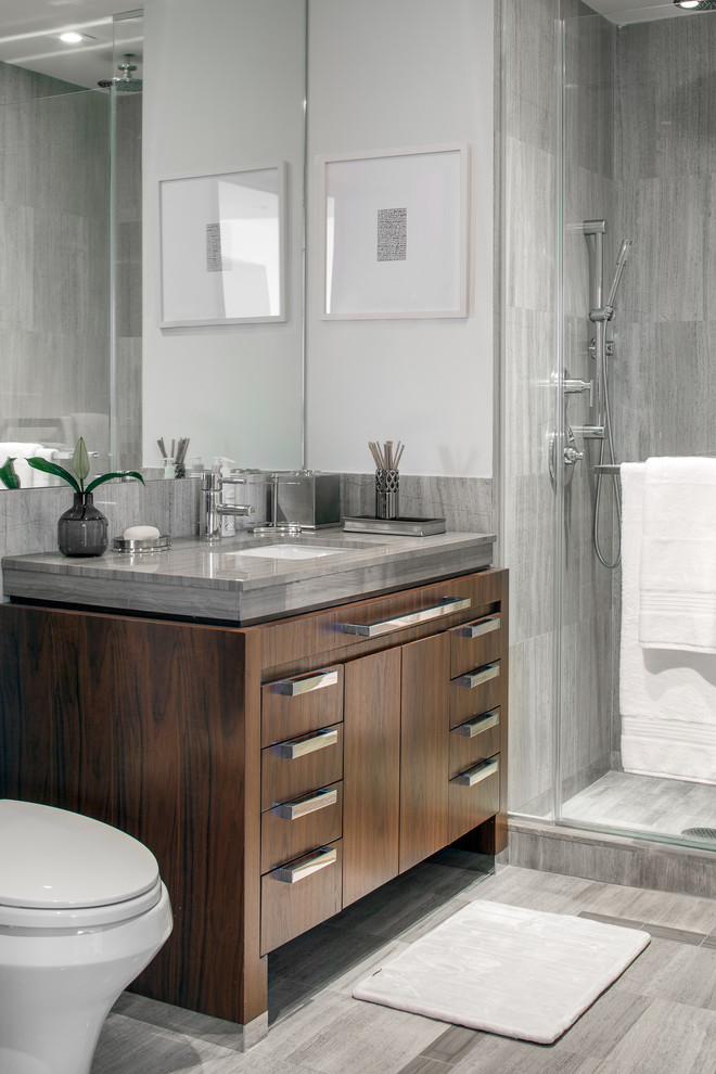 Cette image montre une salle de bain design en bois foncé de taille moyenne avec un carrelage gris, du carrelage en marbre, un sol en marbre, un plan de toilette en marbre, un sol gris, un plan de toilette gris, un mur blanc, un lavabo encastré et un placard à porte plane.