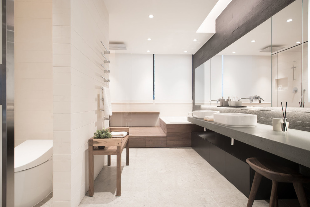 На фото: большая главная ванная комната в стиле модернизм с черными фасадами, накладной ванной, открытым душем, черной плиткой, каменной плиткой, бежевыми стенами, полом из известняка и столешницей из известняка