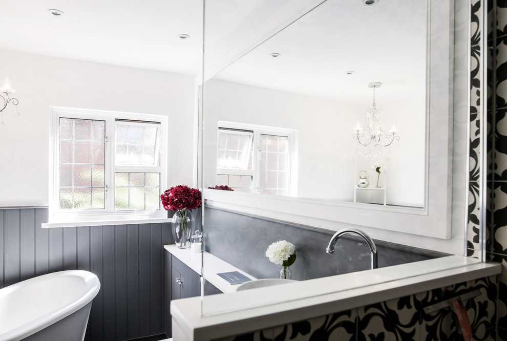 This is an example of a medium sized contemporary family bathroom in Kent with flat-panel cabinets, grey cabinets, a freestanding bath, a corner shower, a wall mounted toilet, black and white tiles, white walls, dark hardwood flooring, a built-in sink, quartz worktops, an open shower and white worktops.