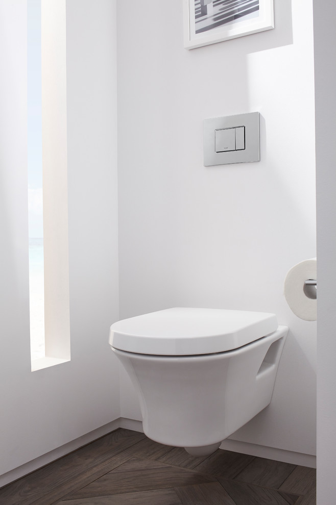 Inredning av ett modernt stort vit vitt toalett, med skåp i shakerstil, vita skåp, en vägghängd toalettstol, vit kakel, porslinskakel, vita väggar, mellanmörkt trägolv, ett undermonterad handfat, bänkskiva i akrylsten och grått golv