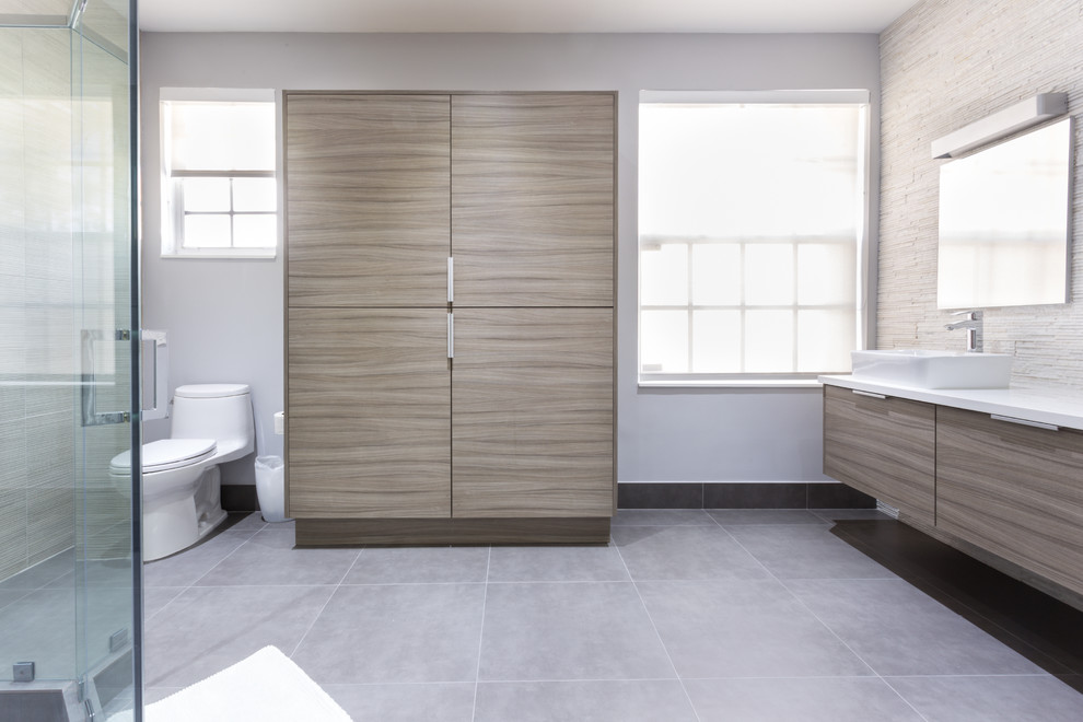 Example of a large minimalist master multicolored tile and porcelain tile porcelain tile corner shower design in Miami with a vessel sink, flat-panel cabinets, gray cabinets, quartz countertops, a one-piece toilet and white walls