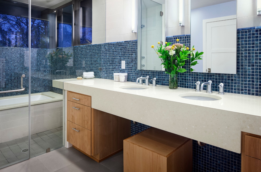 Exemple d'une salle de bain principale tendance en bois brun avec un lavabo encastré, un plan de toilette en quartz modifié, une baignoire encastrée, un carrelage bleu, des carreaux de porcelaine, un sol en carrelage de porcelaine, un placard à porte plane et un combiné douche/baignoire.