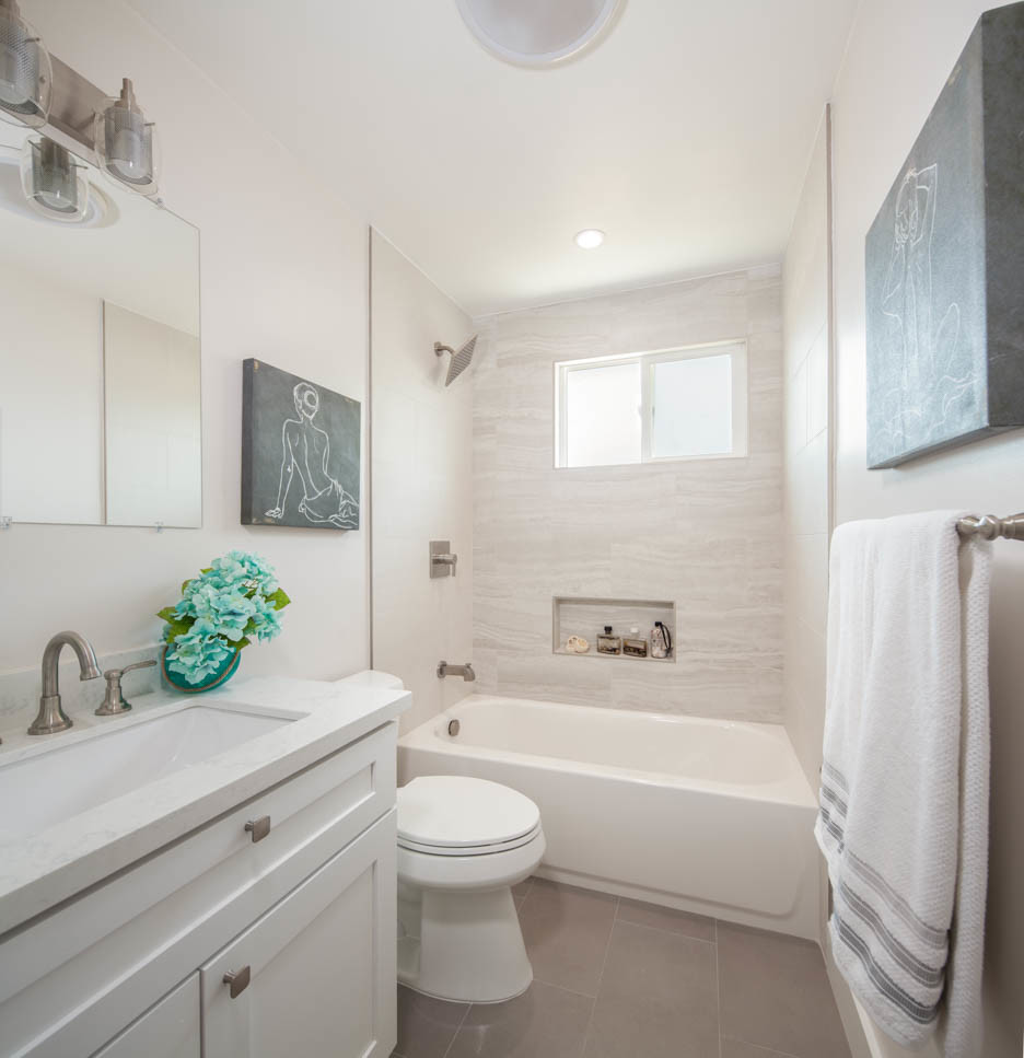 Amerikansk inredning av ett mellanstort vit vitt badrum för barn, med skåp i shakerstil, vita skåp, ett badkar i en alkov, en dusch i en alkov, en toalettstol med hel cisternkåpa, grå kakel, porslinskakel, vita väggar, klinkergolv i porslin, ett undermonterad handfat, bänkskiva i kvarts, grått golv och med dusch som är öppen
