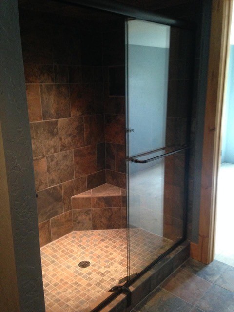 Foto på ett rustikt badrum med dusch, med en dusch i en alkov, en toalettstol med separat cisternkåpa, brun kakel, grå kakel, keramikplattor, grå väggar, klinkergolv i keramik, brunt golv och dusch med skjutdörr