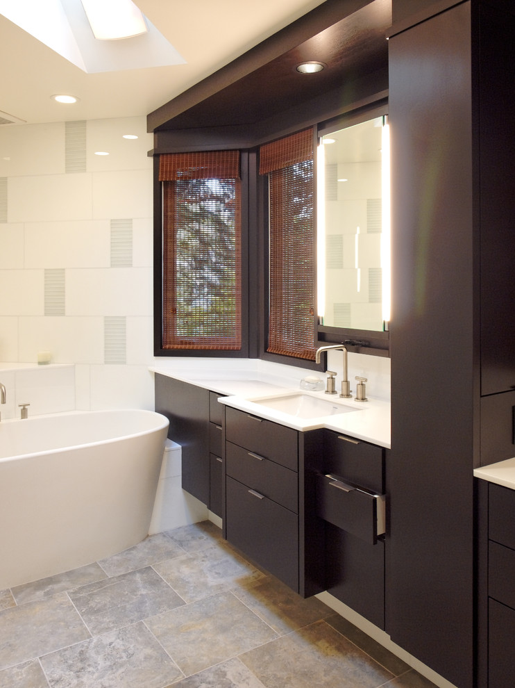 Exemple d'une grande salle de bain principale tendance avec un placard à porte plane, des portes de placard marrons, une baignoire indépendante, WC séparés, un carrelage en pâte de verre, un mur blanc, un sol en calcaire, un lavabo encastré et un plan de toilette en marbre.