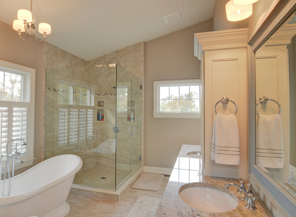 Modelo de cuarto de baño principal tradicional de tamaño medio con armarios estilo shaker, puertas de armario blancas, bañera exenta, ducha esquinera, paredes beige, lavabo bajoencimera y encimera de granito
