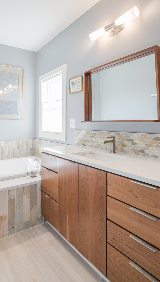 Cette image montre une salle de bain principale vintage en bois brun de taille moyenne avec un placard à porte plane, une baignoire posée, un carrelage bleu, un carrelage vert, un carrelage orange, un carrelage blanc, un carrelage en pâte de verre, un mur bleu, un sol en carrelage de porcelaine, un lavabo encastré et un plan de toilette en quartz.