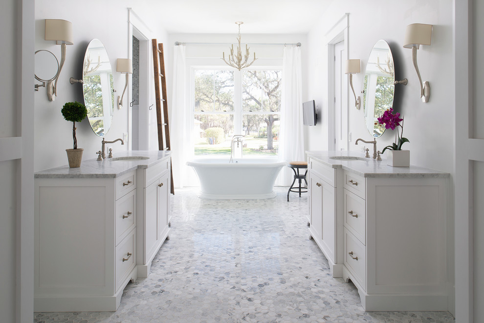 На фото: главная ванная комната в стиле кантри с фасадами в стиле шейкер, белыми фасадами, отдельно стоящей ванной, белыми стенами, врезной раковиной и зеркалом с подсветкой