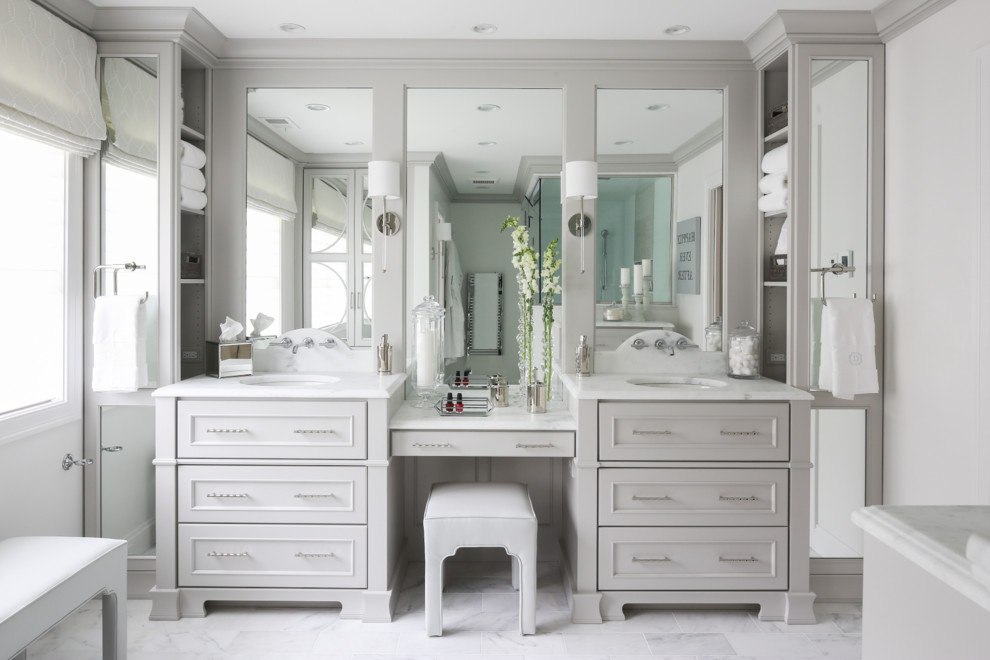 Klassisk inredning av ett stort en-suite badrum, med grå skåp, en toalettstol med separat cisternkåpa, vit kakel, stenkakel, grå väggar, marmorgolv, ett undermonterad handfat, marmorbänkskiva och luckor med infälld panel