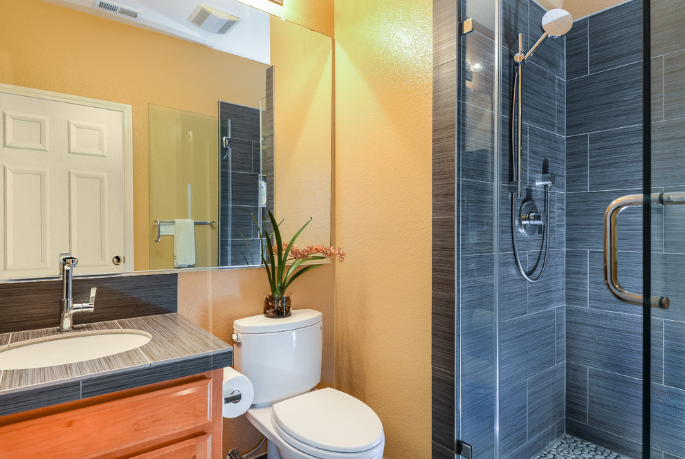 Inspiration pour une petite salle d'eau design en bois brun avec un placard à porte plane, une douche ouverte, WC séparés, un carrelage gris, des carreaux de porcelaine, un mur jaune, un sol en carrelage de céramique, un lavabo posé et un plan de toilette en carrelage.