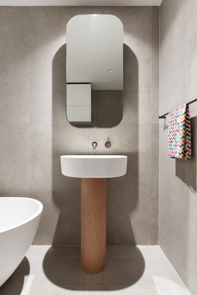 Diseño de cuarto de baño minimalista con bañera exenta, baldosas y/o azulejos grises, lavabo con pedestal y suelo gris