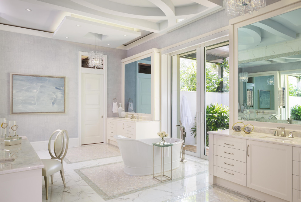 Inredning av ett medelhavsstil mycket stort vit vitt en-suite badrum, med vita skåp, ett fristående badkar, marmorgolv, ett undermonterad handfat, marmorbänkskiva, luckor med infälld panel och grå väggar