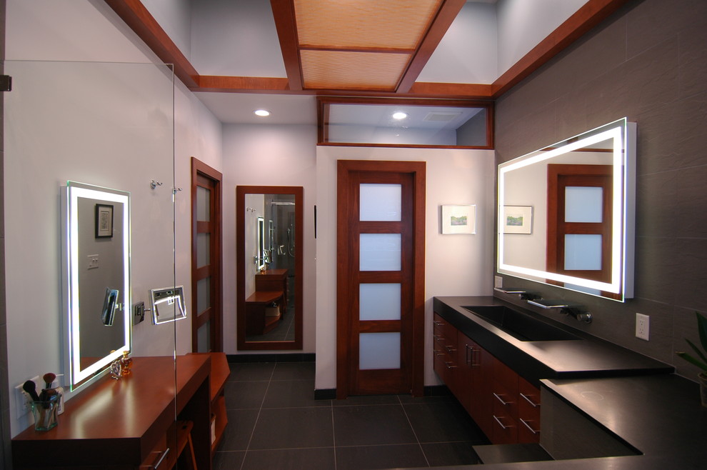 Idee per una stanza da bagno etnica con lavabo rettangolare, ante lisce, ante in legno scuro, piastrelle nere e piastrelle in pietra
