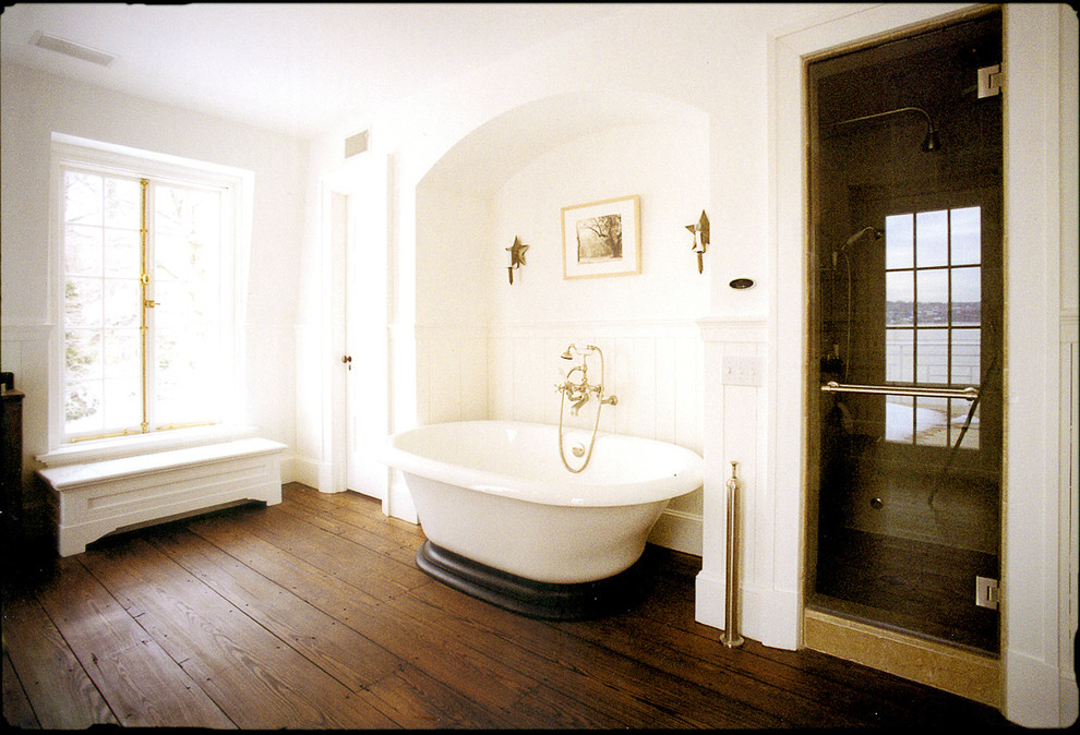 Lantlig inredning av ett mellanstort en-suite badrum, med ett undermonterad handfat, luckor med infälld panel, vita skåp, bänkskiva i kalksten, ett fristående badkar, en dusch i en alkov, en toalettstol med separat cisternkåpa, vita väggar och mörkt trägolv