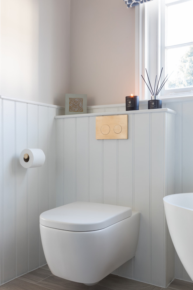 This is an example of a medium sized traditional family bathroom in Kent with a freestanding bath, a corner shower, beige walls, light hardwood flooring, a wall-mounted sink, brown floors and a sliding door.