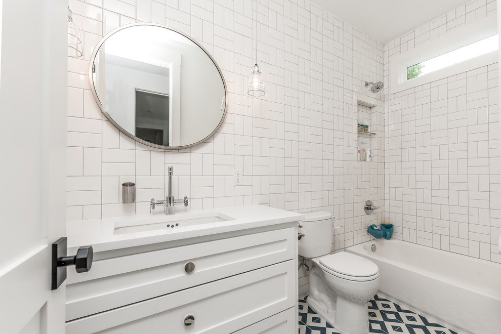 Photo of a medium sized farmhouse family bathroom in Houston with shaker cabinets, white cabinets, a built-in bath, a shower/bath combination, a one-piece toilet, white tiles, cement tiles, white walls, porcelain flooring, a submerged sink, engineered stone worktops, white floors, a hinged door and white worktops.