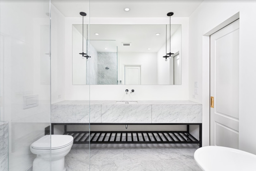Photo of a medium sized modern ensuite bathroom in Ottawa with flat-panel cabinets, white cabinets, a claw-foot bath, a corner shower, a one-piece toilet, marble tiles, white walls, marble flooring, a submerged sink, marble worktops, white floors, an open shower and white worktops.