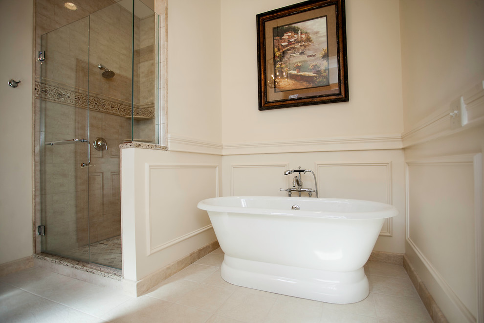 Klassisk inredning av ett stort en-suite badrum, med ett undermonterad handfat, luckor med upphöjd panel, beige skåp, granitbänkskiva, ett fristående badkar, en toalettstol med separat cisternkåpa, beige kakel, beige väggar och klinkergolv i porslin