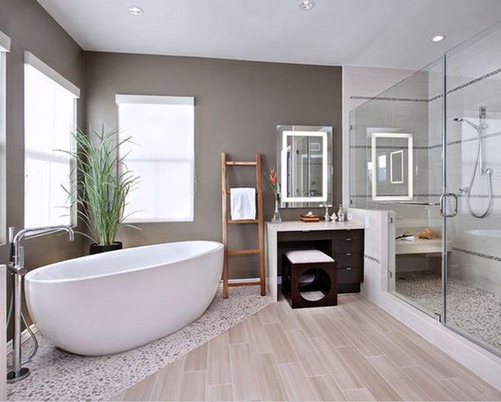 Bild på ett stort funkis en-suite badrum, med släta luckor, skåp i mörkt trä, ett fristående badkar, en dusch i en alkov, beige kakel, kakel i småsten, grå väggar, klinkergolv i porslin och bänkskiva i akrylsten