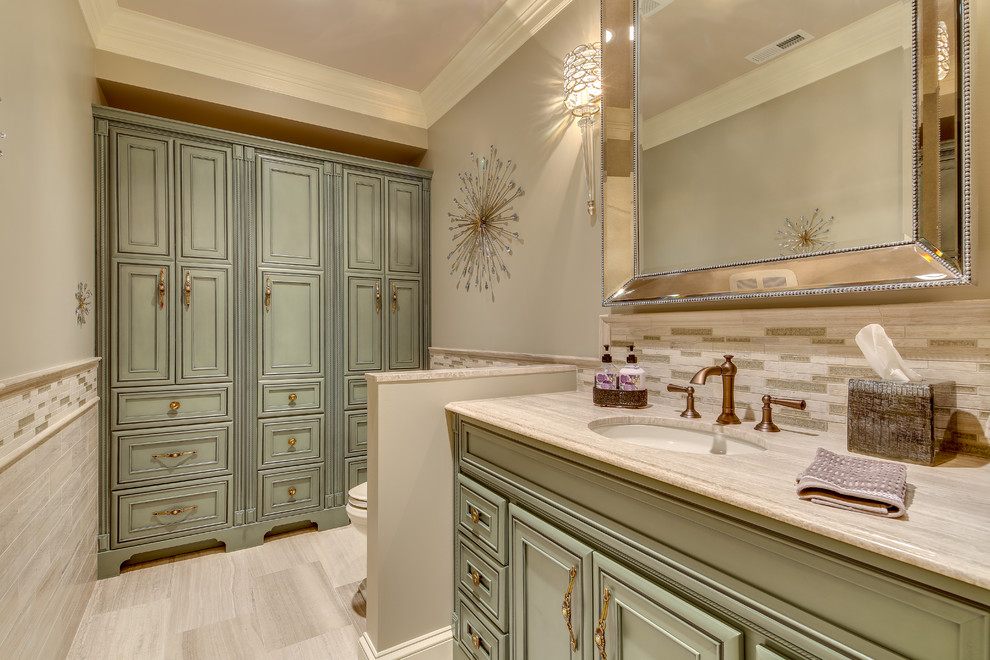 Immagine di una stanza da bagno chic con lavabo sottopiano, ante con riquadro incassato e piastrelle beige
