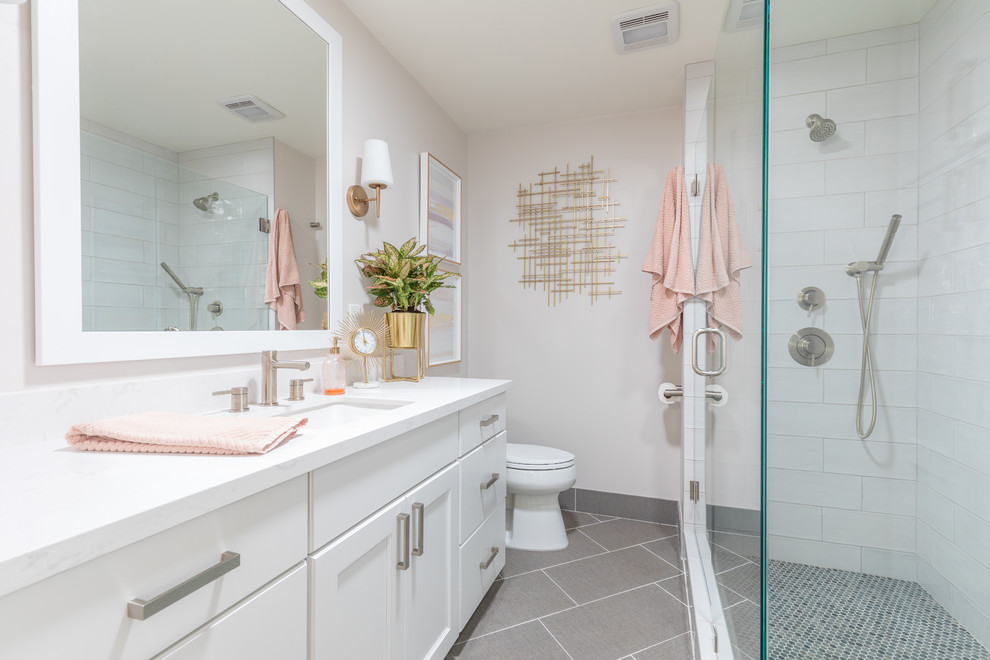 Idée de décoration pour une salle de bain tradition avec un placard à porte shaker, des portes de placard blanches, une douche d'angle, un carrelage blanc, un mur gris, un lavabo encastré, un sol gris et un plan de toilette blanc.