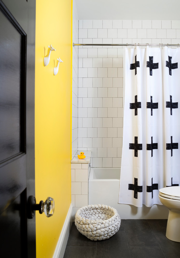 Modern inredning av ett mellanstort badrum för barn, med ett undermonterad handfat, släta luckor, vita skåp, bänkskiva i betong, ett badkar i en alkov, en dusch/badkar-kombination, en toalettstol med hel cisternkåpa, vit kakel, porslinskakel, gula väggar och klinkergolv i porslin