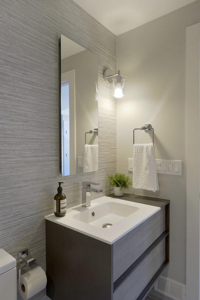 Bathroom - mid-sized modern 3/4 gray tile and porcelain tile porcelain tile and gray floor bathroom idea in New York with furniture-like cabinets, gray cabinets, a one-piece toilet, gray walls, an integrated sink and solid surface countertops