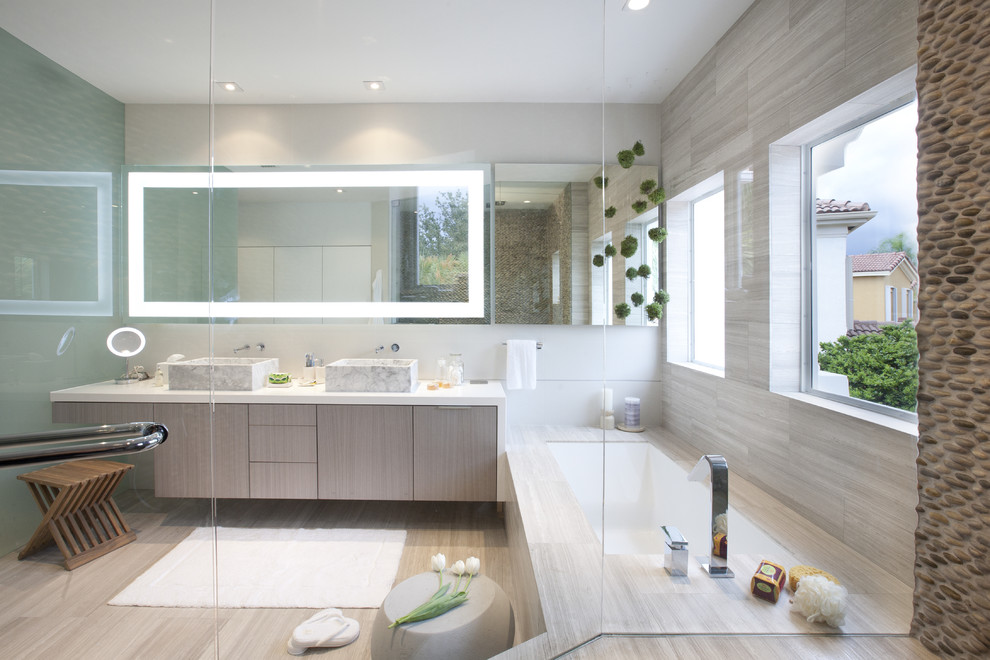 Пример оригинального дизайна: ванная комната в стиле модернизм с настольной раковиной, плоскими фасадами, светлыми деревянными фасадами, ванной в нише и бежевой плиткой