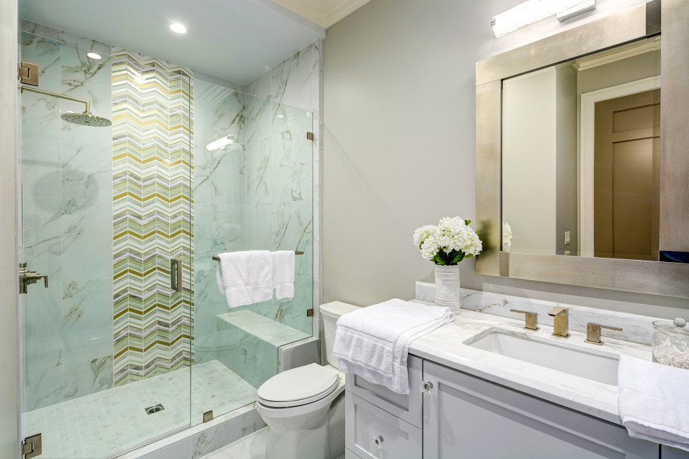 Réalisation d'une salle de bain tradition avec un placard à porte shaker, des portes de placard grises, un carrelage multicolore, mosaïque, un mur gris, un lavabo encastré, un sol blanc et un plan de toilette blanc.