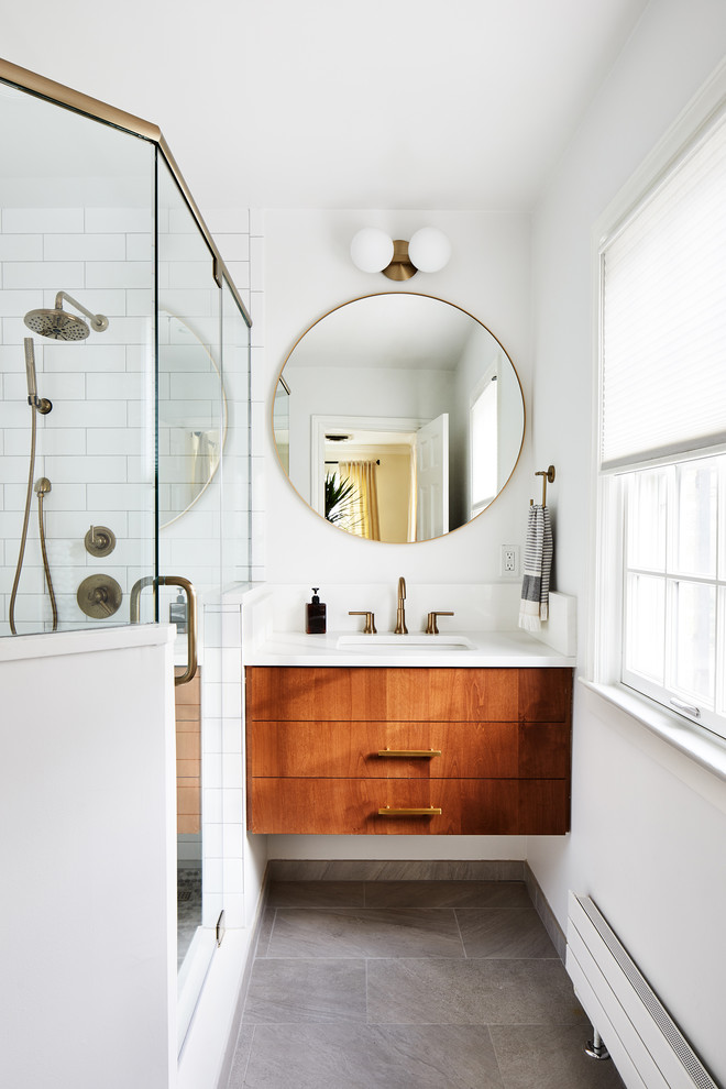 Inredning av ett modernt litet vit vitt badrum, med släta luckor, skåp i mellenmörkt trä, en hörndusch, vit kakel, vita väggar, ett undermonterad handfat, grått golv och dusch med gångjärnsdörr