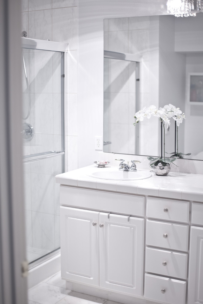 Example of a small transitional master white tile marble floor doorless shower design in Seattle with flat-panel cabinets, white cabinets, tile countertops, a one-piece toilet, an undermount sink and gray walls