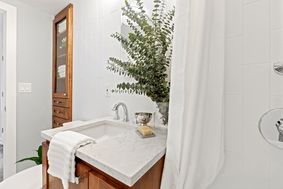 На фото: маленькая главная ванная комната в стиле неоклассика (современная классика) с фасадами в стиле шейкер, фасадами цвета дерева среднего тона, ванной в нише, душем над ванной, унитазом-моноблоком, разноцветной плиткой, керамогранитной плиткой, зелеными стенами, бетонным полом, врезной раковиной, столешницей из искусственного кварца, серым полом, шторкой для ванной и белой столешницей для на участке и в саду с