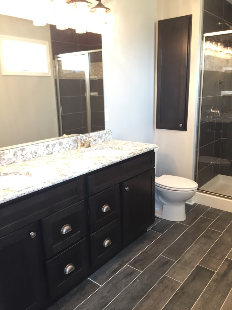 Aménagement d'une salle de bain principale craftsman en bois foncé de taille moyenne avec un placard à porte shaker, un mur gris, un lavabo encastré et un plan de toilette en granite.