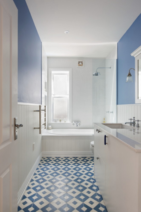 Inredning av ett klassiskt mellanstort en-suite badrum, med släta luckor, vita skåp, ett platsbyggt badkar, en dusch/badkar-kombination, en toalettstol med hel cisternkåpa, blå kakel, cementkakel, blå väggar, cementgolv, ett undermonterad handfat och bänkskiva i kvarts