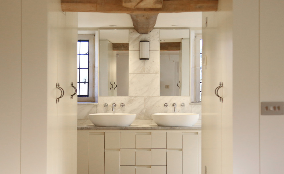 Immagine di una stanza da bagno country di medie dimensioni con ante lisce, ante bianche, piastrelle bianche, piastrelle in pietra, top in marmo e top bianco