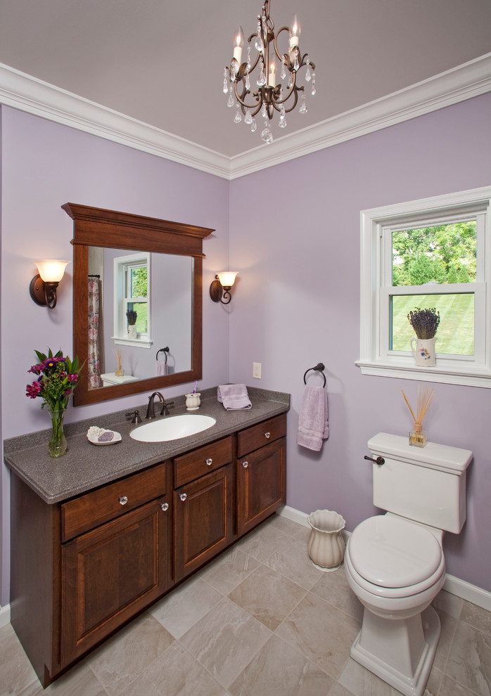 Photo of a medium sized traditional family bathroom in Philadelphia with medium wood cabinets, a one-piece toilet, an integrated sink, raised-panel cabinets, solid surface worktops, beige tiles, porcelain tiles, purple walls and porcelain flooring.