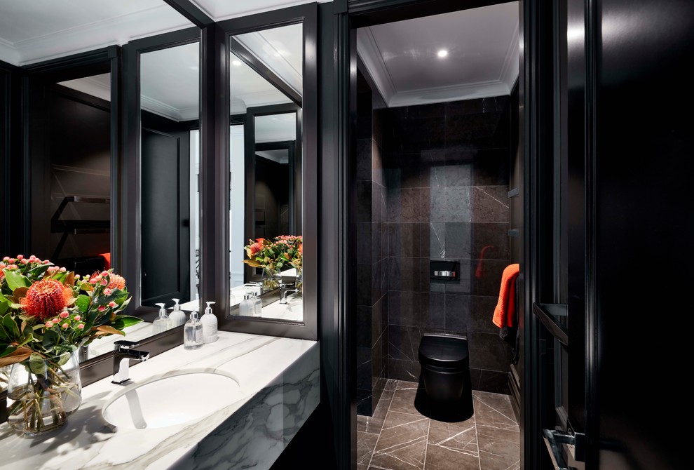 Foto på ett funkis vit badrum, med svart kakel, svarta väggar, ett undermonterad handfat, en dusch i en alkov, en toalettstol med hel cisternkåpa, marmorkakel, marmorgolv, marmorbänkskiva och brunt golv