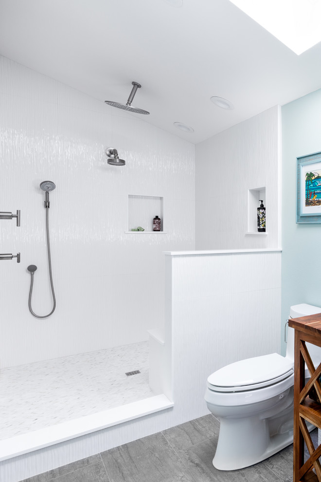 Inredning av ett maritimt mellanstort vit vitt en-suite badrum, med luckor med lamellpanel, skåp i mellenmörkt trä, ett fristående badkar, en kantlös dusch, en toalettstol med hel cisternkåpa, blå kakel, keramikplattor, blå väggar, klinkergolv i porslin, ett nedsänkt handfat, bänkskiva i kvartsit, brunt golv och med dusch som är öppen