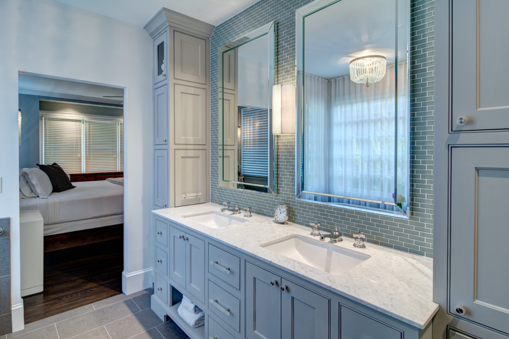 На фото: большая главная ванная комната в классическом стиле с врезной раковиной, фасадами с утопленной филенкой, синими фасадами, столешницей из гранита, отдельно стоящей ванной, синей плиткой, стеклянной плиткой, белыми стенами и полом из керамогранита