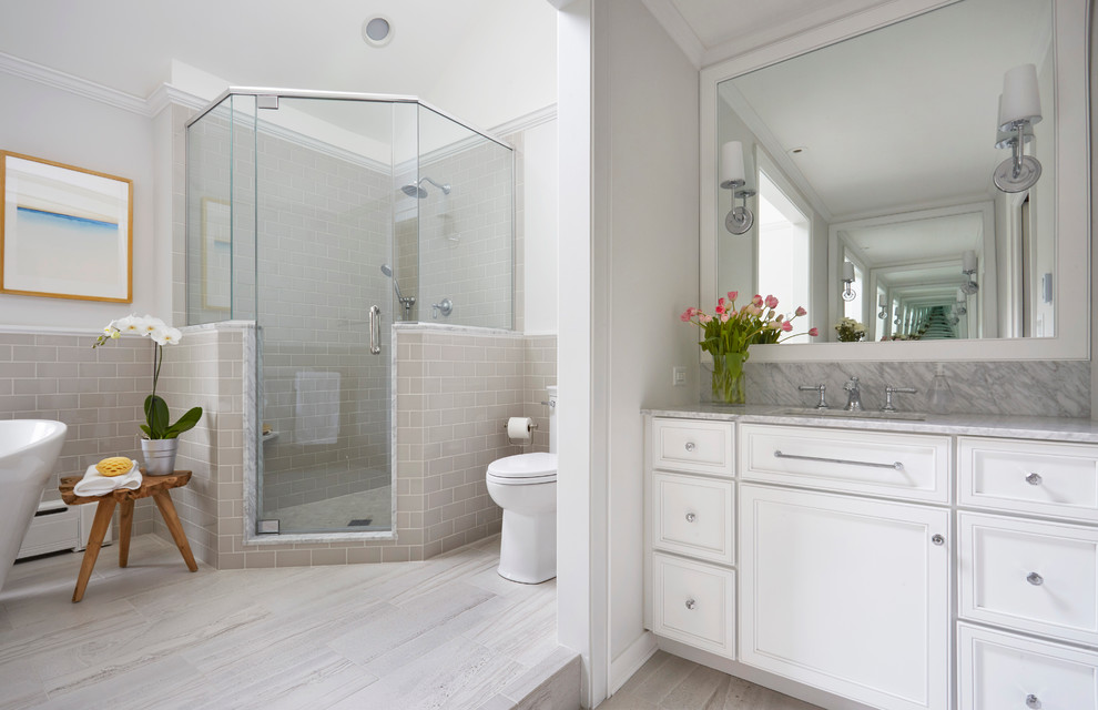 Large traditional ensuite half tiled bathroom in Chicago with recessed-panel cabinets, white cabinets, a freestanding bath, a corner shower, ceramic tiles, a submerged sink, marble worktops, a one-piece toilet, grey tiles, grey walls and porcelain flooring.