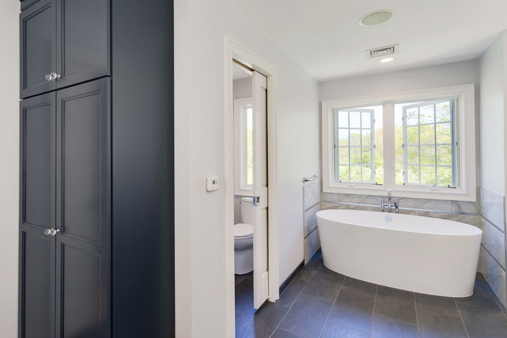 Пример оригинального дизайна: большая главная ванная комната в стиле неоклассика (современная классика) с плоскими фасадами, синими фасадами, отдельно стоящей ванной, открытым душем, раздельным унитазом, серой плиткой, керамогранитной плиткой, серыми стенами, полом из керамогранита, врезной раковиной, столешницей из гранита, серым полом, открытым душем и серой столешницей