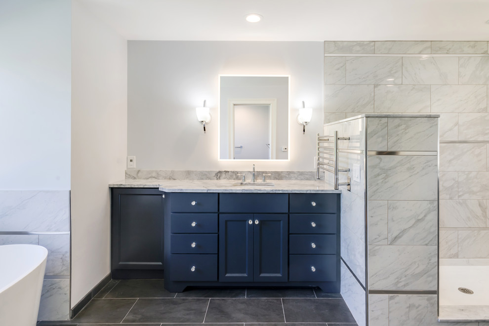 Inspiration for a large classic ensuite bathroom in Philadelphia with flat-panel cabinets, blue cabinets, a freestanding bath, a walk-in shower, a two-piece toilet, grey tiles, porcelain tiles, grey walls, porcelain flooring, a submerged sink, granite worktops, grey floors, an open shower and grey worktops.