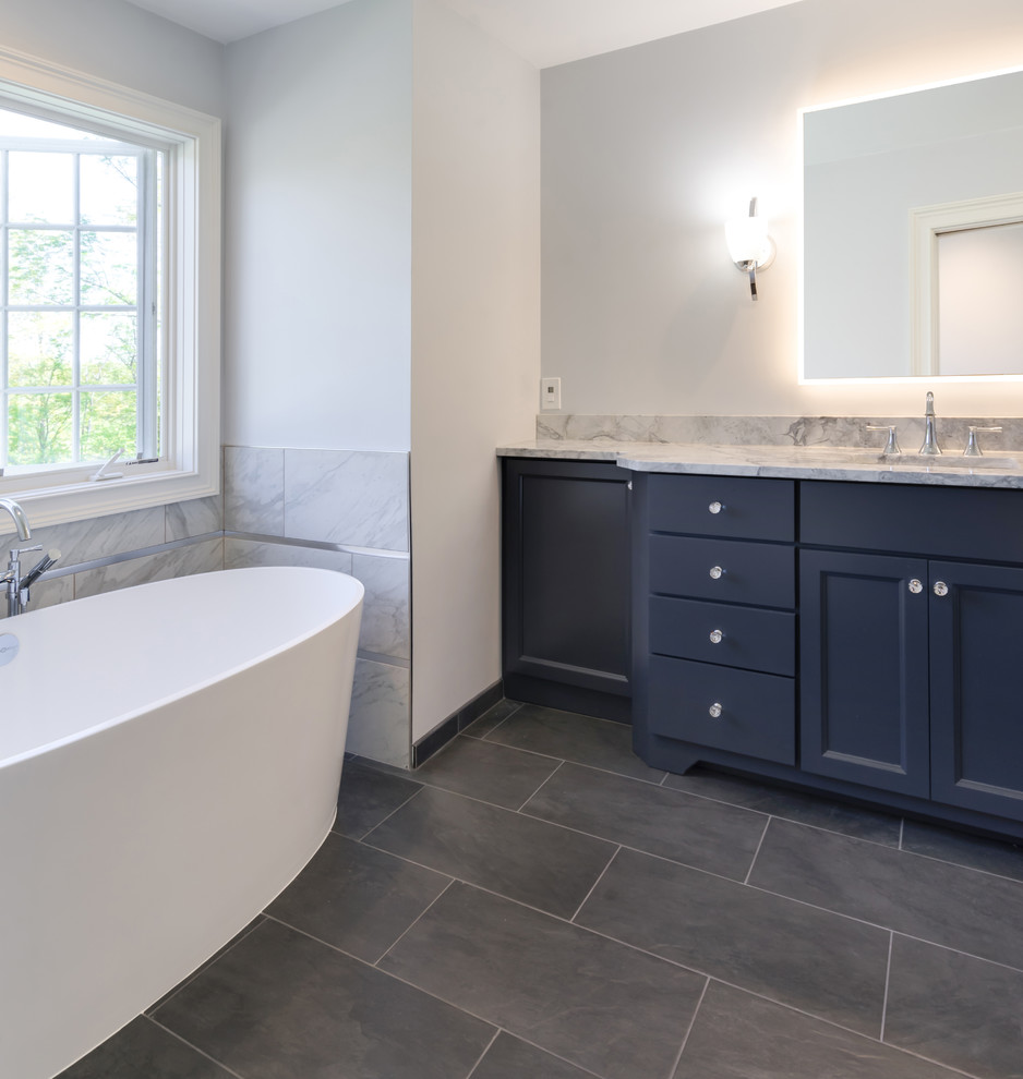 Пример оригинального дизайна: большая главная ванная комната в стиле неоклассика (современная классика) с плоскими фасадами, синими фасадами, отдельно стоящей ванной, открытым душем, раздельным унитазом, серой плиткой, керамогранитной плиткой, серыми стенами, полом из керамогранита, врезной раковиной, столешницей из гранита, серым полом, открытым душем и серой столешницей