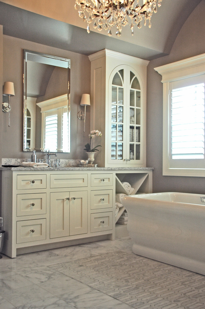 Photo of a large country ensuite bathroom in Chicago with white cabinets, a freestanding bath, grey walls, marble flooring, a submerged sink, engineered stone worktops, recessed-panel cabinets, an alcove shower, a two-piece toilet, grey tiles, marble tiles, grey floors and a hinged door.