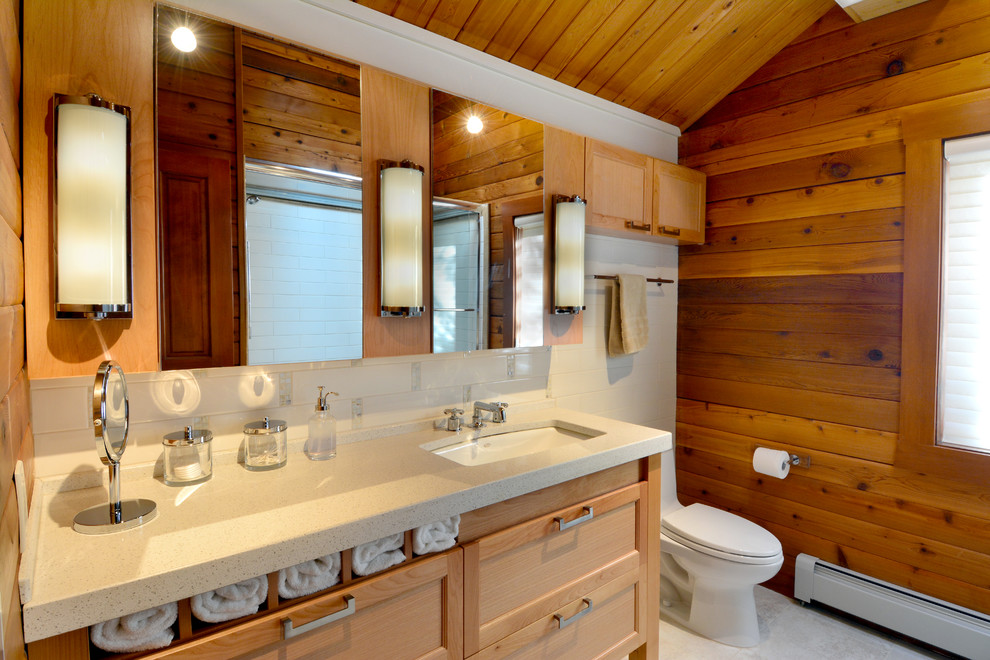 シアトルにある広いラスティックスタイルのおしゃれなバスルーム (浴槽なし) (シェーカースタイル扉のキャビネット、淡色木目調キャビネット、白いタイル、アンダーカウンター洗面器、茶色い壁、アルコーブ型シャワー、一体型トイレ	、サブウェイタイル、セラミックタイルの床、白い床、引戸のシャワー、ベージュのカウンター、照明) の写真